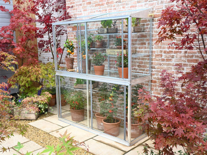 This is the Hampton Greenhouse without coating, its a two storey greenhouse, that includes shelving. The greenhouse is 5&quot; tall, the background is of a paved patio on which the greenhouse stands with red and green acer plants to the background and foreground.