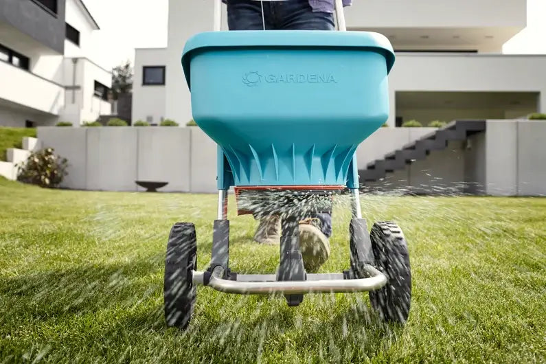 Gardena Spreader XL distributing fertilizer over a large lawn area in residential backyard