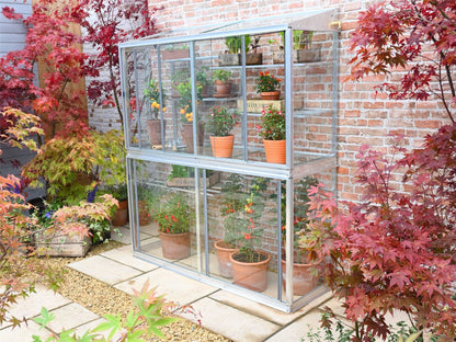 This is the Hampton Greenhouse without coating, its a two storey greenhouse, that includes shelving. The greenhouse is 5&quot; tall, the background is of a paved patio on which the greenhouse stands with red and green acer plants to the background and foreground.